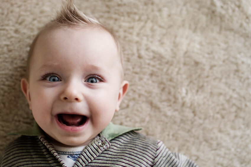 Laughing baby boy lying on a carpet